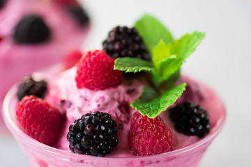 Homemade sorbet made from fresh berries with mint in glass bowl on a gray background.