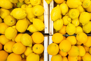Bright yellow lemons in wooden boxes at farmer's market or grocery store. May be used for background. Top view.