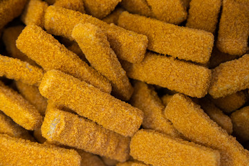 Golden fish cticks in pile background, frozen food section at supermarket.