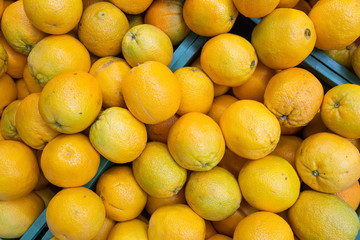 Bright yellow oranges in wooden boxes at farmer's market or grocery front view. May be used for background. Top view.