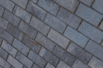 Diagonal view at weathered grunge gray stone brick wall with dark cement grid lines