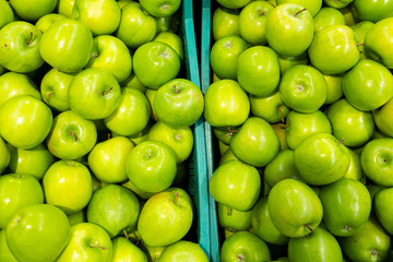 Green shiny apple at farmer's market plastic trays. May be used for agriculture overview, inspiration purpose abstract background.