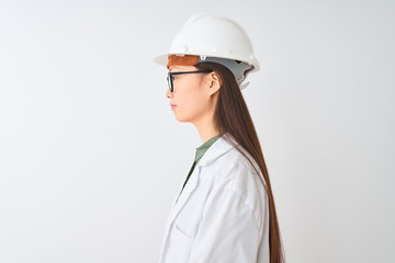 Young chinese engineer woman wearing coat helmet glasses over isolated white background looking to side, relax profile pose with natural face with confident smile.