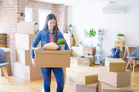 Beautiful asian young woman holding boxes, smiling happy moving to a new home