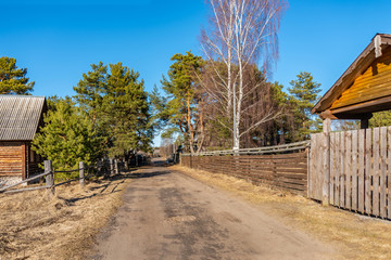 Fototapeta na wymiar A typical street in the suburban areas in Russia with a dirt road