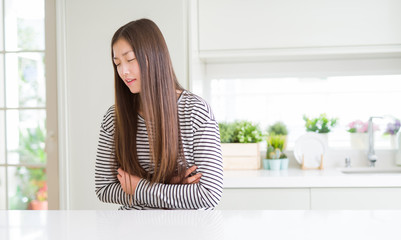 Beautiful Asian woman wearing stripes sweater with hand on stomach because nausea, painful disease feeling unwell. Ache concept.