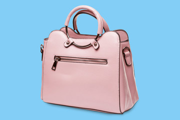 elegant pink female bag with metal fittings, on a blue background with a shadow