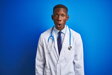 African american doctor man wearing stethoscope standing over isolated blue background afraid and shocked with surprise expression, fear and excited face.