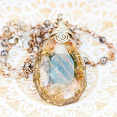 Orgonite pendant on mineral stone chain necklace placed on decorative background