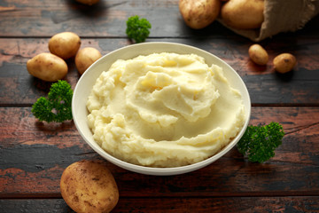 Mashed potatoes in white bowl on wooden rustic table. Healthy food