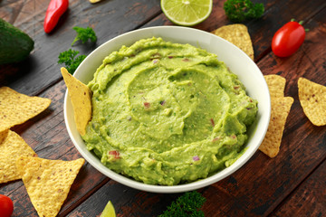 Bowl of fresh Guacamole with nachos chips and herbs. Healthy Vegan, Vegetables food.