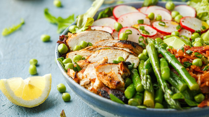 Cobb salad bowl with grilled chicken breast, asparagus, avocado, radishes and bacon