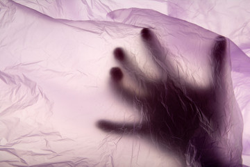 Hand in plastic bag. Murder concept. Concept view. Close up. Soft puple texture