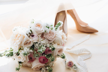 bride with wedding bouquet. Wedding bouquet and shoes on the windowsill. Bridal bouquet, daylight and tulle. High key. Wedding photo.