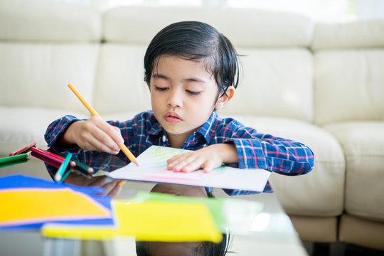 Cute child using a color pencil to draw on a paper