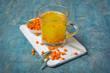 Glass cup of healthy tea with fresh ripe sea buckthorn berries