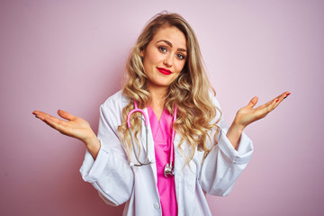 Young beautiful doctor woman using stethoscope over pink isolated background clueless and confused...