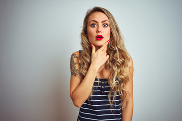Young beautiful woman wearing stripes t-shirt standing over white isolated background Looking fascinated with disbelief, surprise and amazed expression with hands on chin