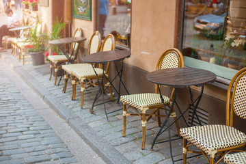 Empty tables in between dining hours. Old fashioned cafe terrace in a summer day