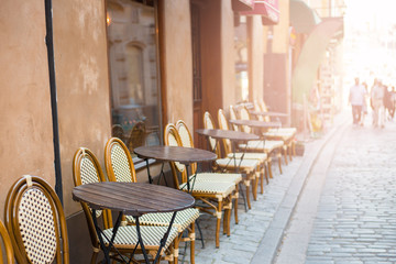 Empty tables in between dining hours. Old fashioned cafe terrace in a summer day
