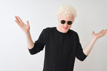 Young albino man wearing black t-shirt and sunglasess standing over isolated white background...