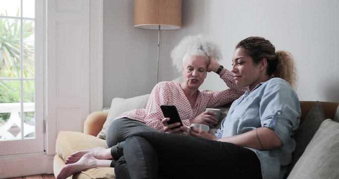 Senior adult woman looking at smartphone with daughter