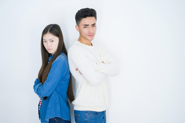 Beautiful young asian couple over white isolated background skeptic and nervous, disapproving...