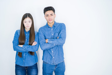 Beautiful young asian couple over white isolated background skeptic and nervous, disapproving...
