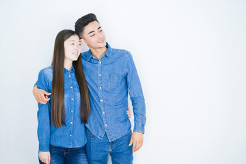 Naklejka premium Beautiful young asian couple over white isolated background looking away to side with smile on face, natural expression. Laughing confident.
