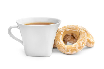 Cup of tea with dried bagels on white.