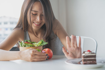 Woman on dieting for good health concept. Close up female using hand push out her favourite cake and choose salad vegetables for good health. - obrazy, fototapety, plakaty
