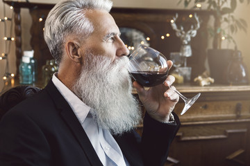 Handsome bearded senior man drinking red wine