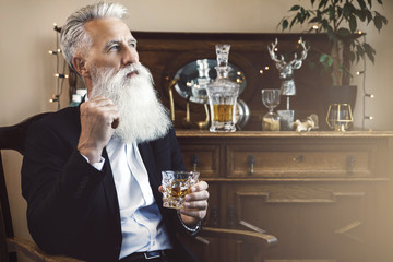 Handsome bearded senior man with a glass of whiskey