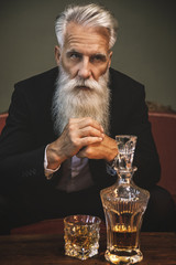 Handsome bearded senior man drinking whiskey