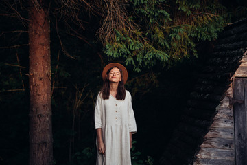 Woman pretty wear amazing white dress and hat on forest and wooden wigwam background . Perfect plase for ceremony. © gartmanart