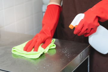 house maid cleaning sink in the kitchen with sponge and cleanser.