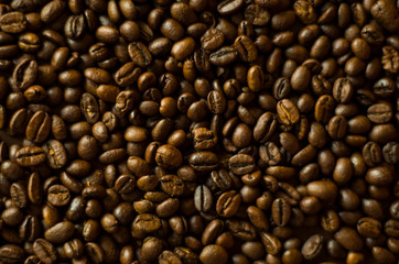 Aromatic roasted coffee beans at the brown wooden background