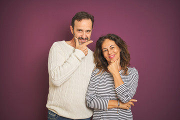Naklejka premium Beautiful middle age couple wearing winter sweater over isolated purple background looking confident at the camera with smile with crossed arms and hand raised on chin. Thinking positive.