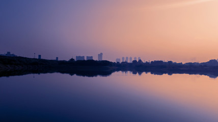 Skyscrapers and trees with reservoir at dusk time