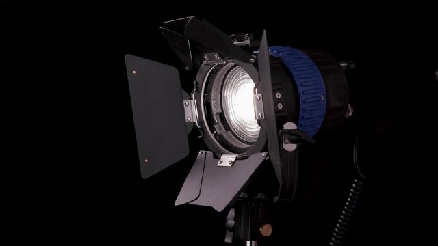 A spotlight with a Fresnel lens rotates on a black background