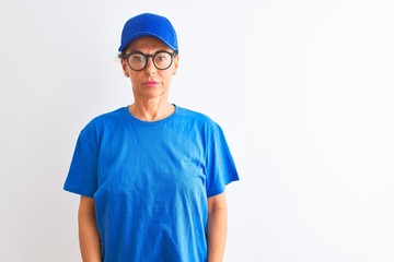 Senior deliverywoman wearing cap and glasses standing over isolated white background with serious expression on face. Simple and natural looking at the camera.