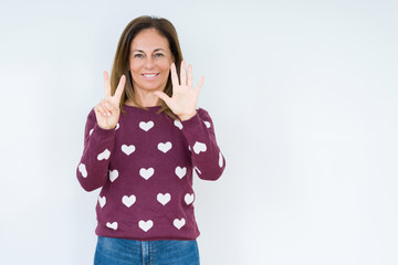 Beautiful middle age woman wearing heart sweater over isolated background showing and pointing up with fingers number seven while smiling confident and happy.