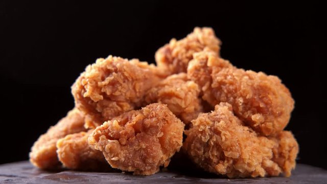 Crispy fried chicken wings and legs with french fries on a wooden table rotation 360 degrees. Breaded Crispy chicken, fried potato tasty dinner. 4K UHD video footage. Ultra high definition 3840X2160