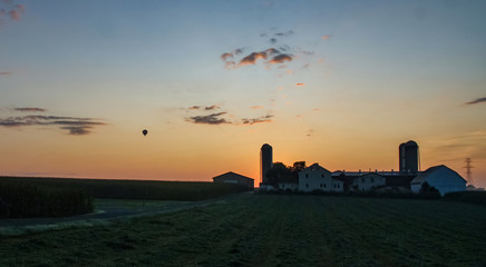 Fototapeta premium Sunrise Over an Amish Farm with Blues and Reds with Hot air Balloon