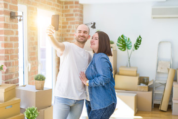 Young couple taking a picture photo using smartphone at new home, smiling happy for moving to new apartment