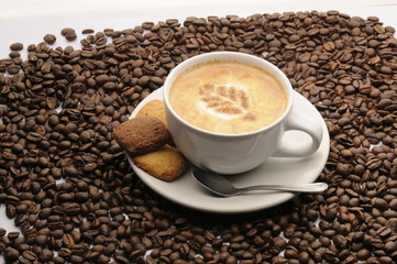 Taza de café con galletas y granos esparcidos