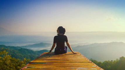 Young woman sits and enjoys Ngisis hill view - obrazy, fototapety, plakaty