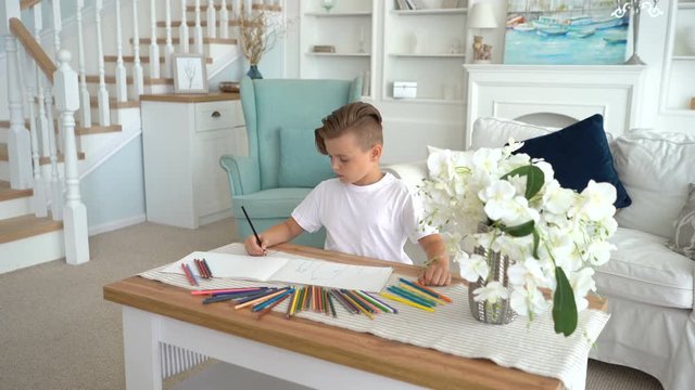 Little boy learns to draw with colored pencils