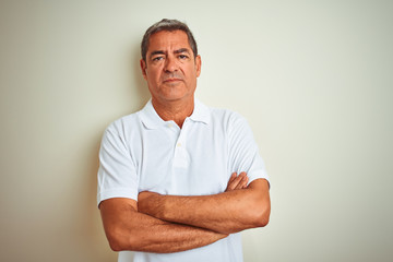 Handsome middle age man wearing polo standing over isolated white background skeptic and nervous, disapproving expression on face with crossed arms. Negative person.