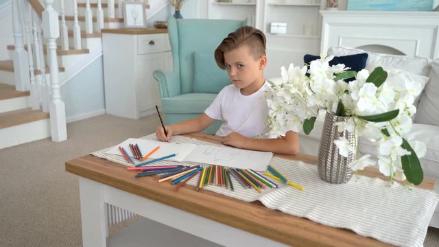 Talented boy draws color pictures on white sheet